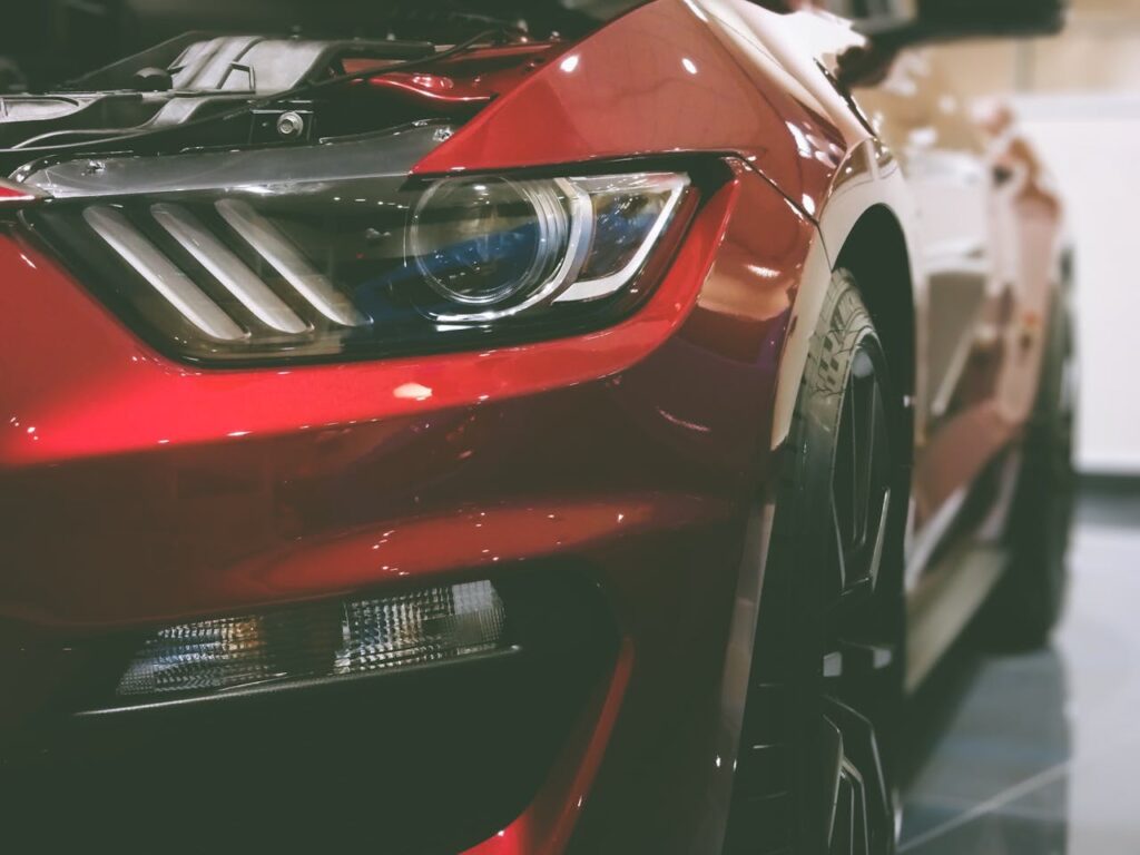 Detailed shot of a shiny red sports car's headlight showcasing luxury design.