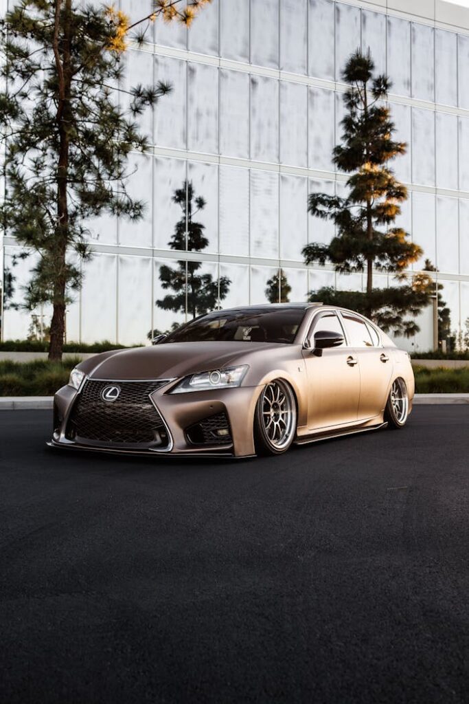 A sleek Lexus GS with a matte paint finish, showcased at a car meet outdoors in daylight.