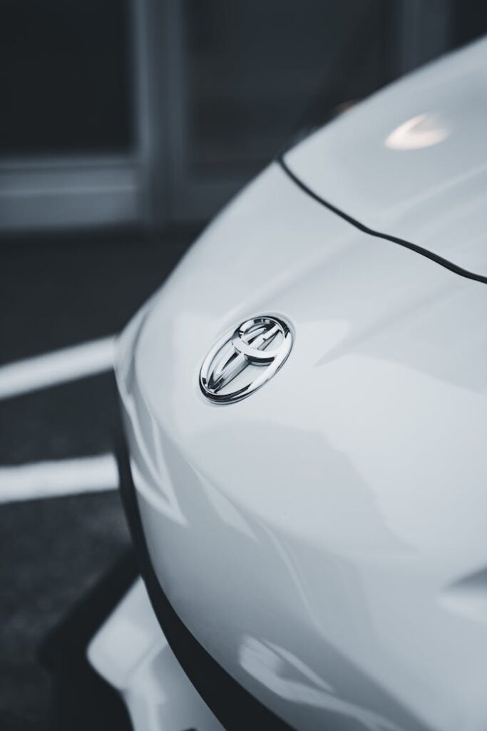 Detailed close-up of a white Toyota sports car in a parking lot, focusing on the logo.