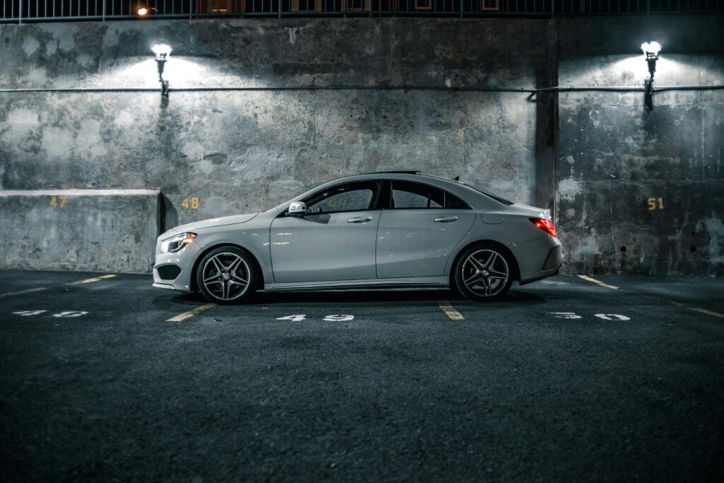 A sleek luxury car parked in an urban lot at night, illuminated by streetlights.